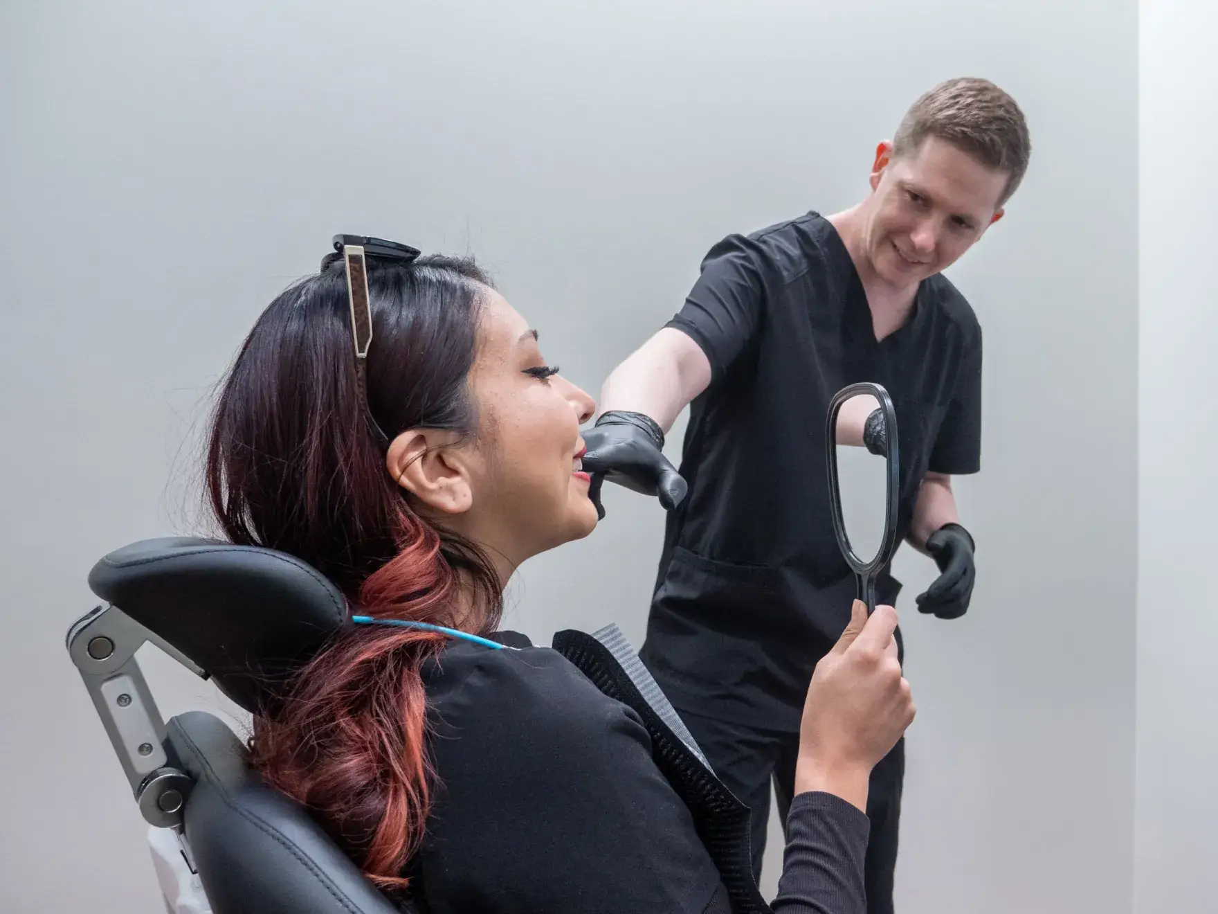 A dentist explains a dental image on a screen to a patient sitting nearby.
