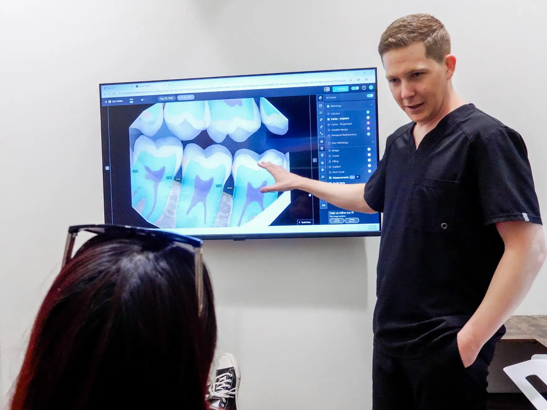 A person with red hair examines dental X-ray images on a computer screen at a dental office.