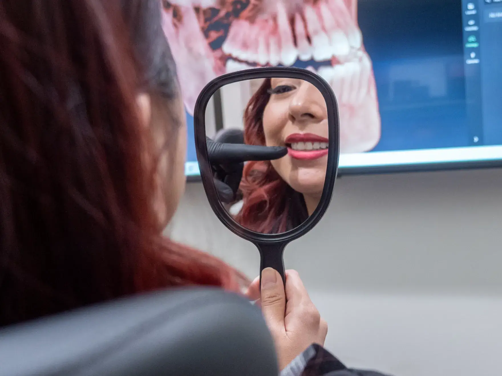 Two people in black uniforms pointing dental tools towards the camera, standing by a reception counter.