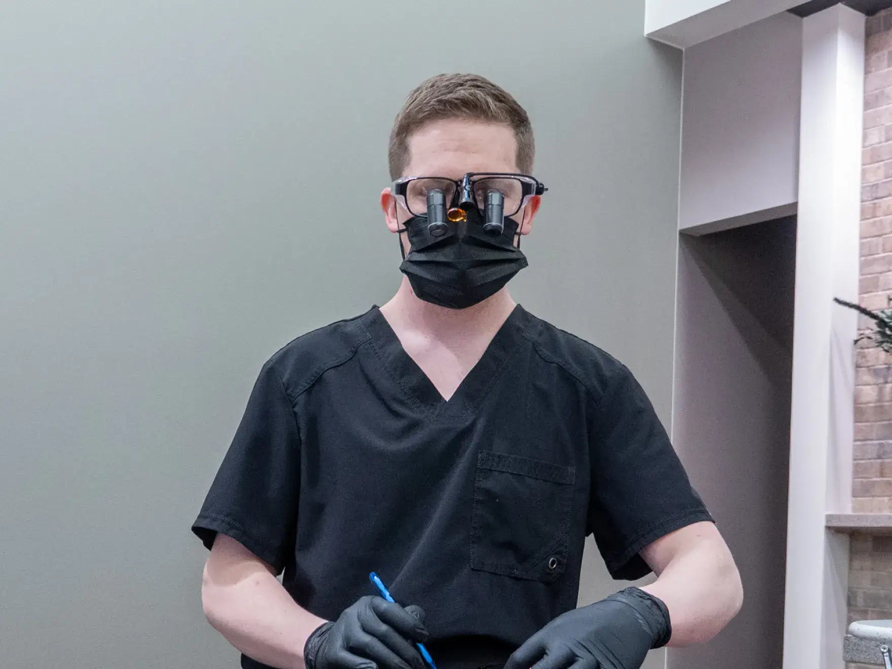A person in a black outfit points to a 3D jaw X-ray displayed on a screen.
