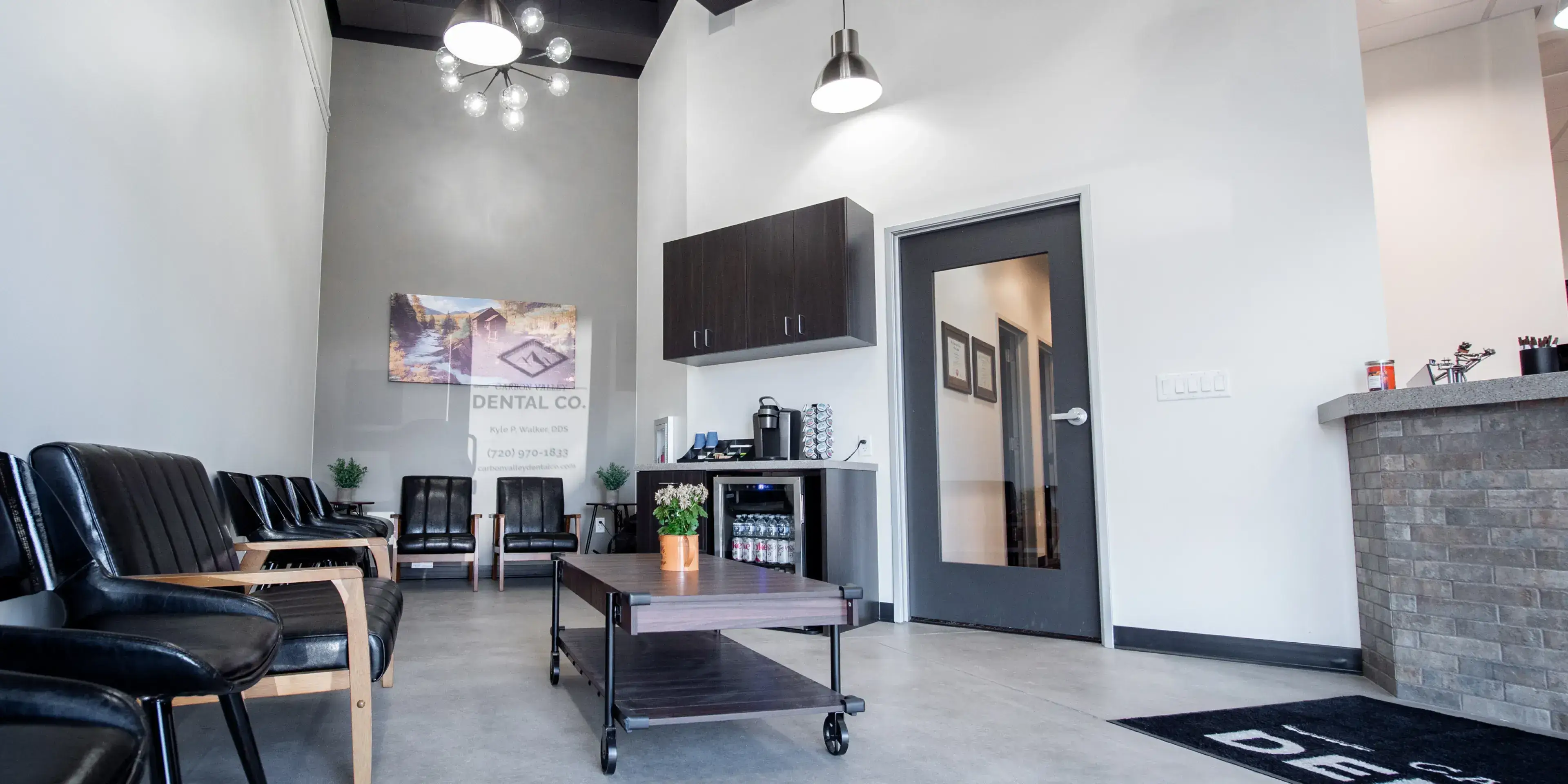 A person looks in a hand mirror, checking their teeth, with a dental x-ray on a screen nearby.