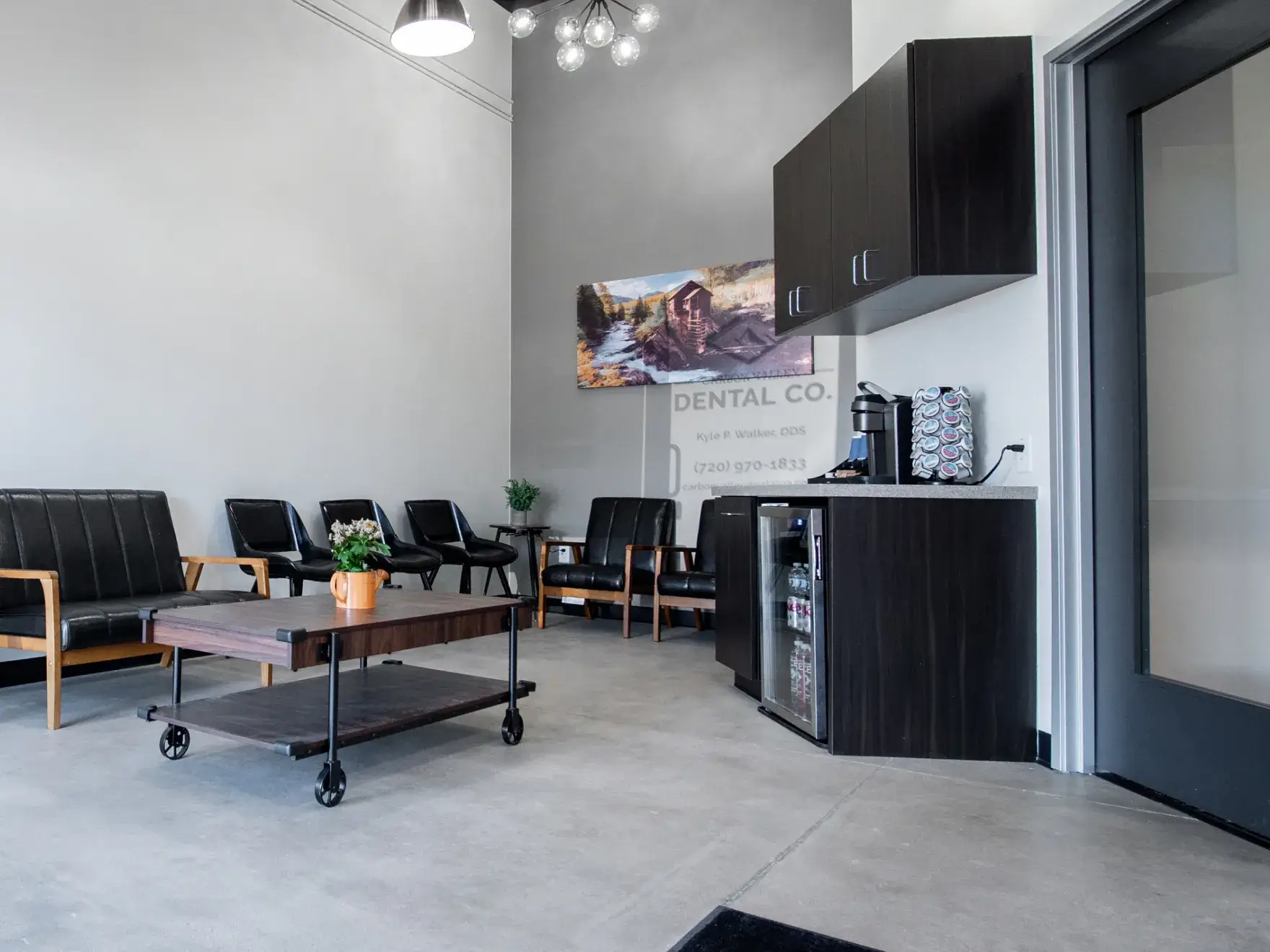 A man and a woman in black uniforms smiling, standing indoors near a counter.