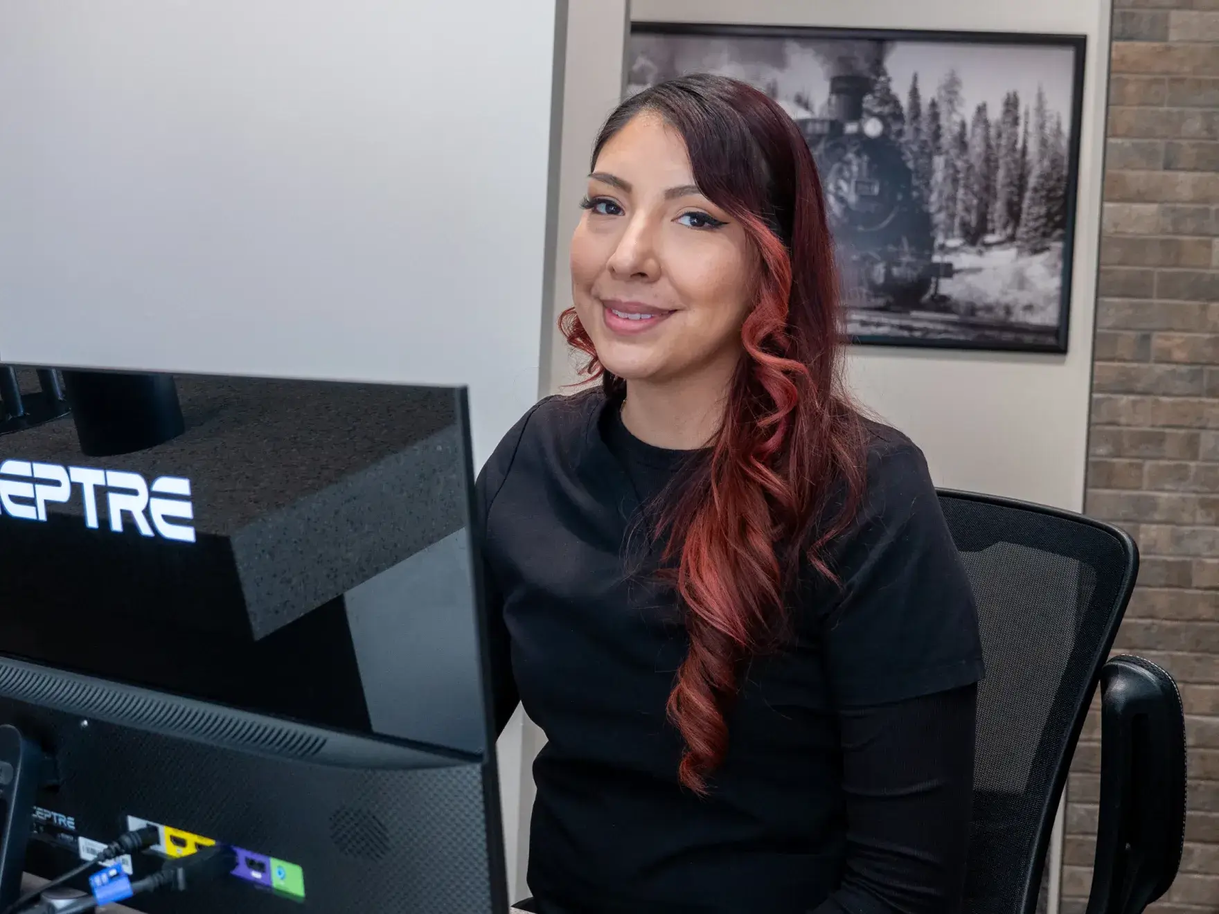 Two people in black uniforms stand back-to-back, smiling and crossing their arms indoors.