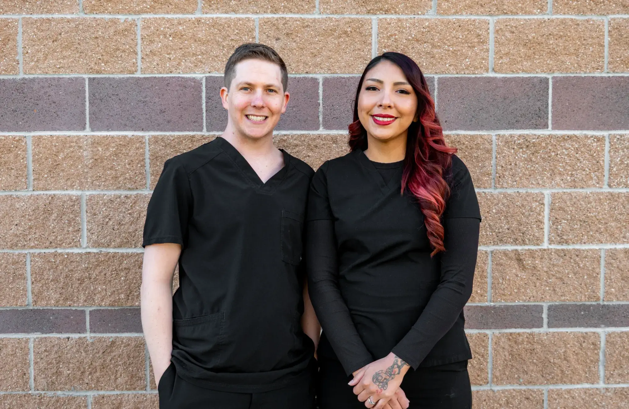 Modern dental office waiting room with black chairs, a wooden table, and a beverage station.