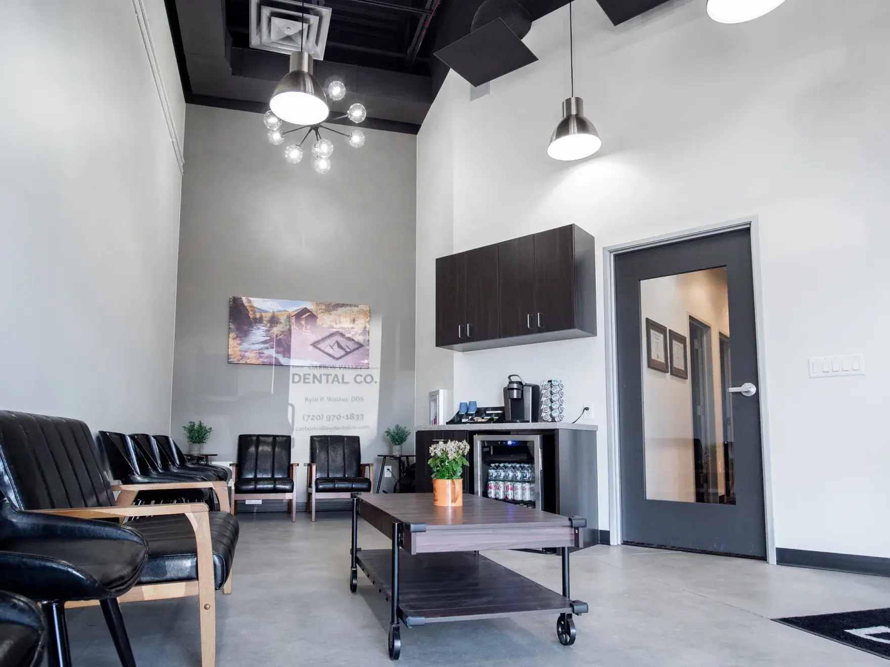 A dental clinic and other businesses in a shopping plaza with cars parked in front.