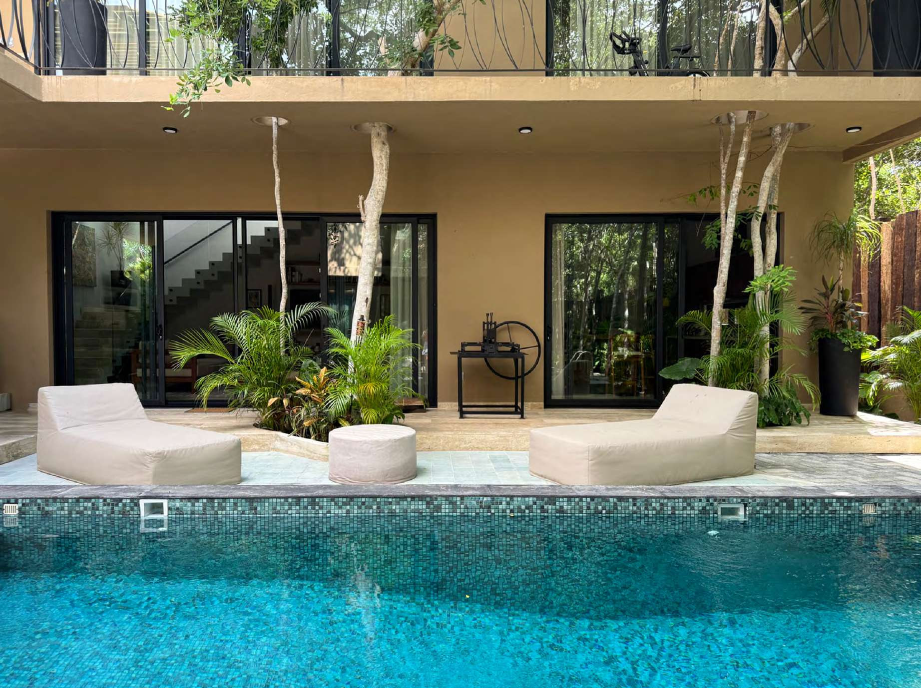 Poolside loungers on travertine terrace at House Yaxche Tulum
