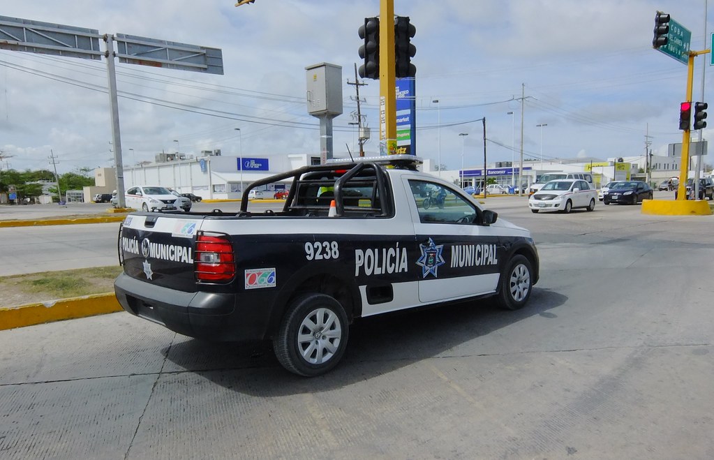 A Policia Municipal pickup truck at a sunny intersection in Tulum