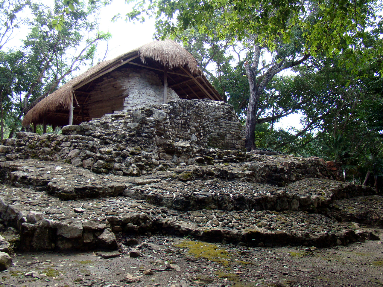 A palapa shelter protecting a stone Maya building at the Xel-Ha archaeological zone in Tulum