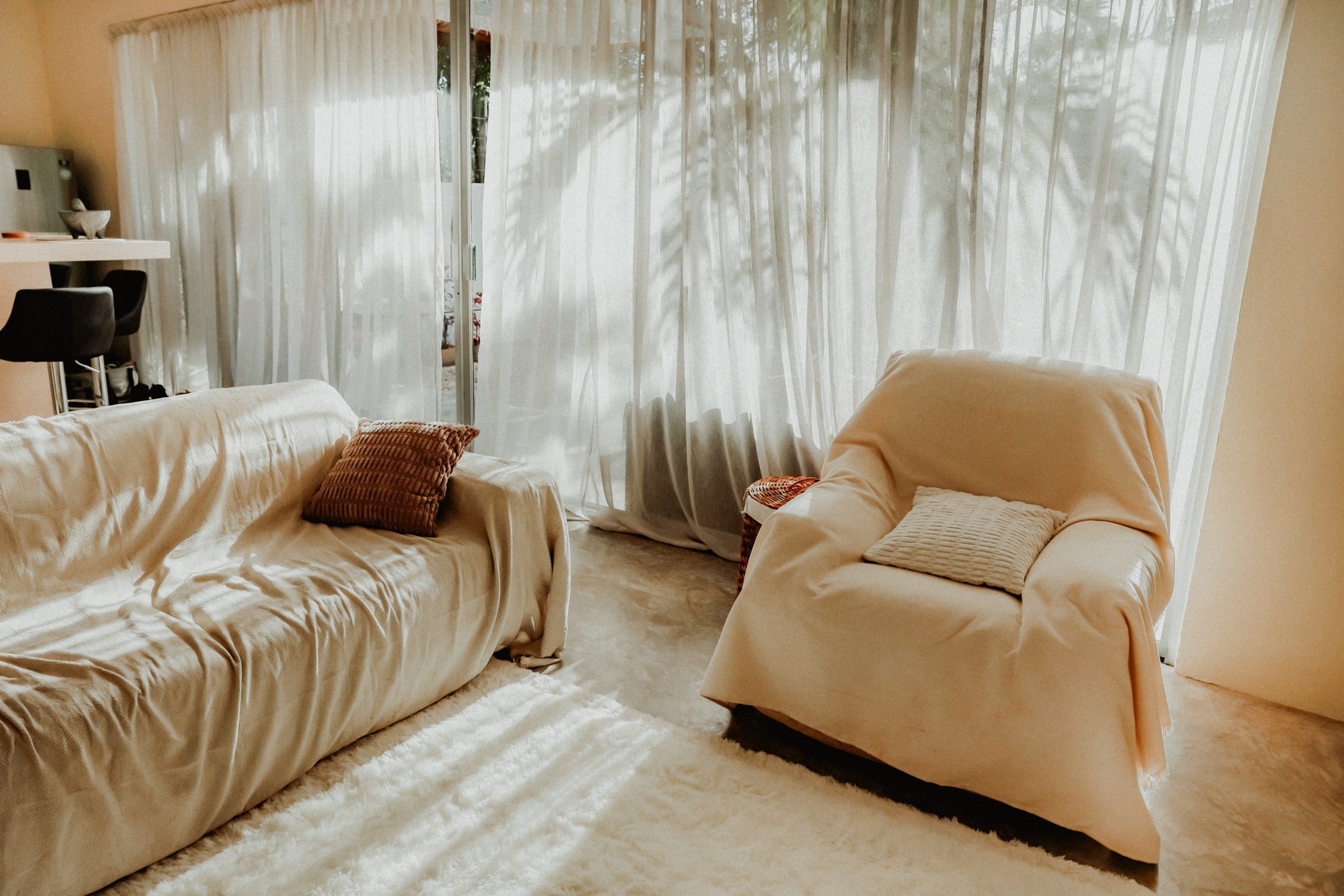 Living room with two deep cream sofas and sheer curtains filtering the afternoon light