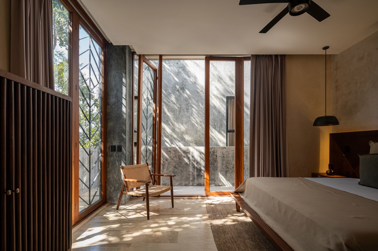 Bedroom with full height glazing opening to planting, bed and reading chair