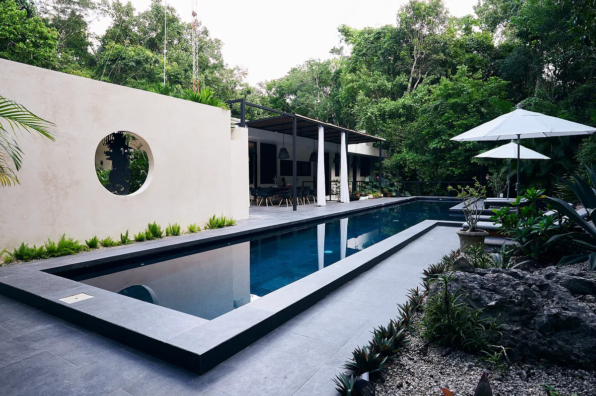 Lap pool beside a white villa surrounded by jungle in Los Arboles, Tulum