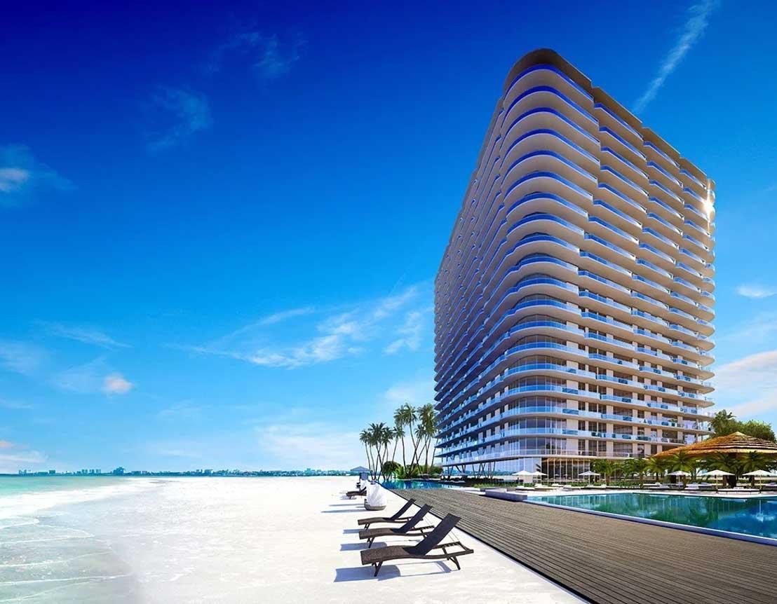 Curved beachfront residential tower on white sand and turquoise water in Cancun