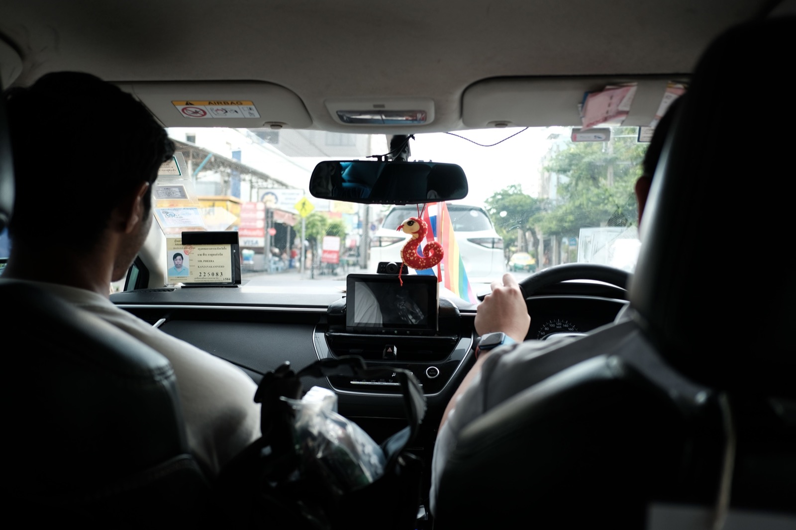 The view from the back seat of a taxi, the driver at the wheel and a meter on the dashboard