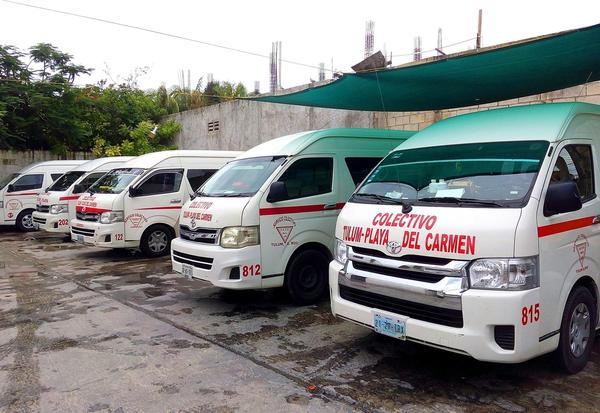 A line of white Colectivo Tulum to Playa del Carmen shared vans parked at their station