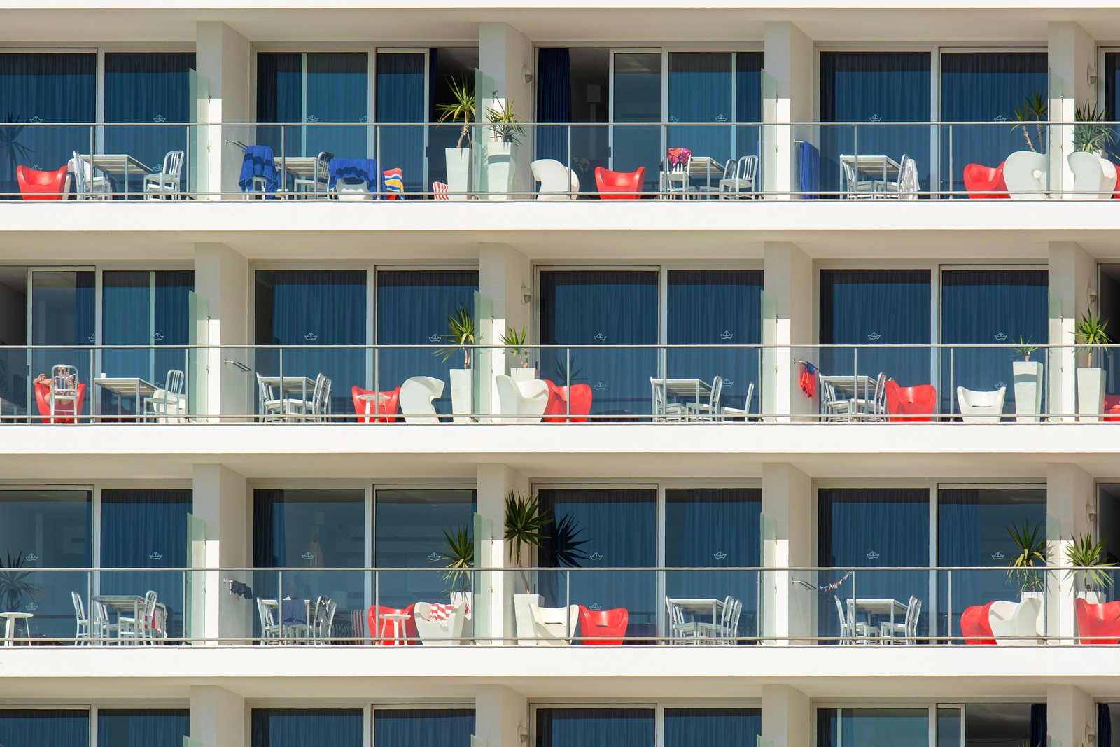 Rows of balconies on a large beachfront hotel block, each with its own seating