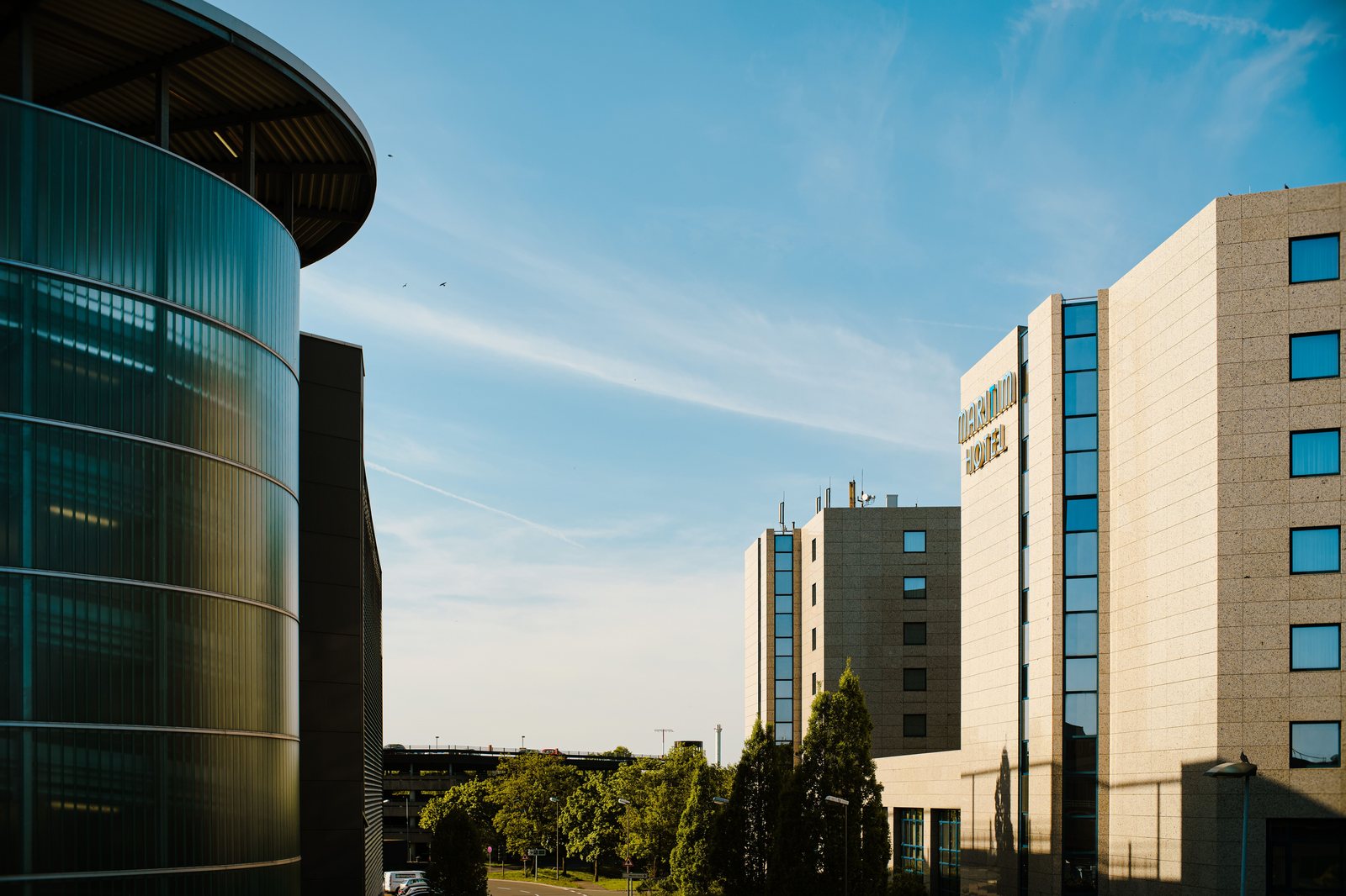 A modern curved glass building on a landscaped campus under clear sky
