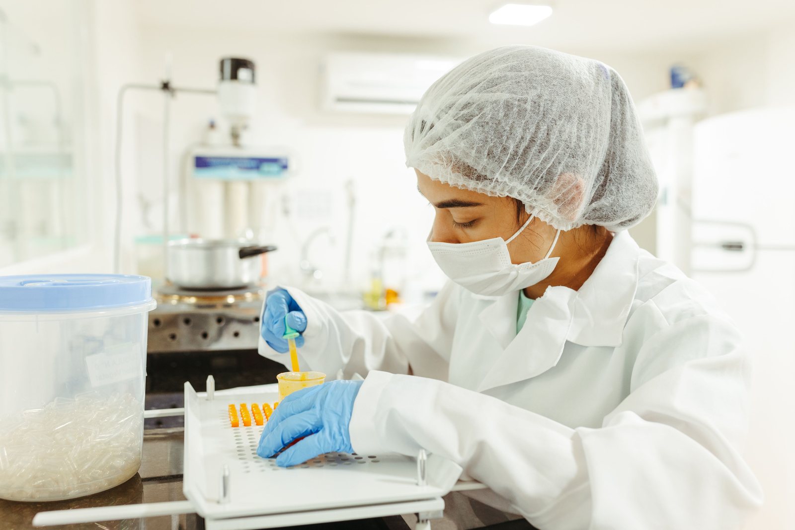 A technician in full protective clothing working at a laboratory bench