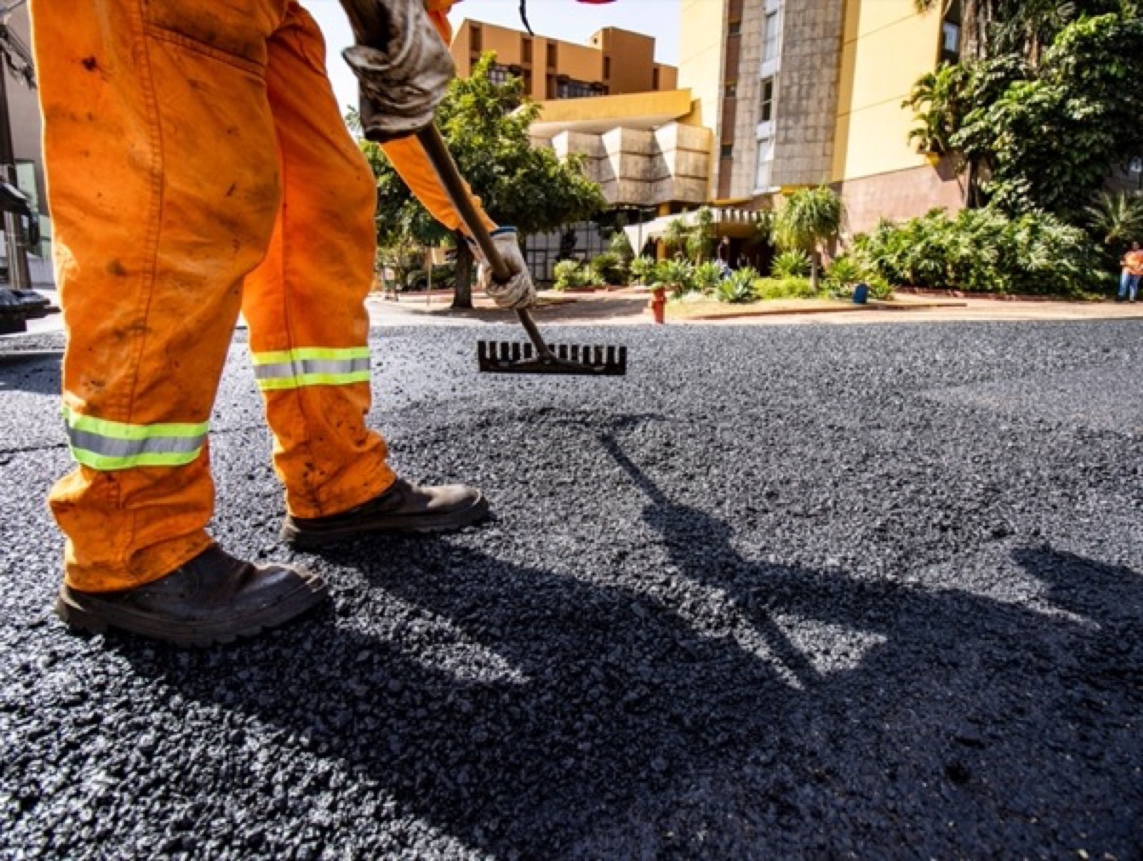 A road crew spreading fresh asphalt by hand
