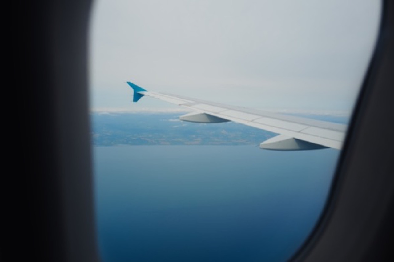 The wing of an airliner seen from a window seat above a coastline
