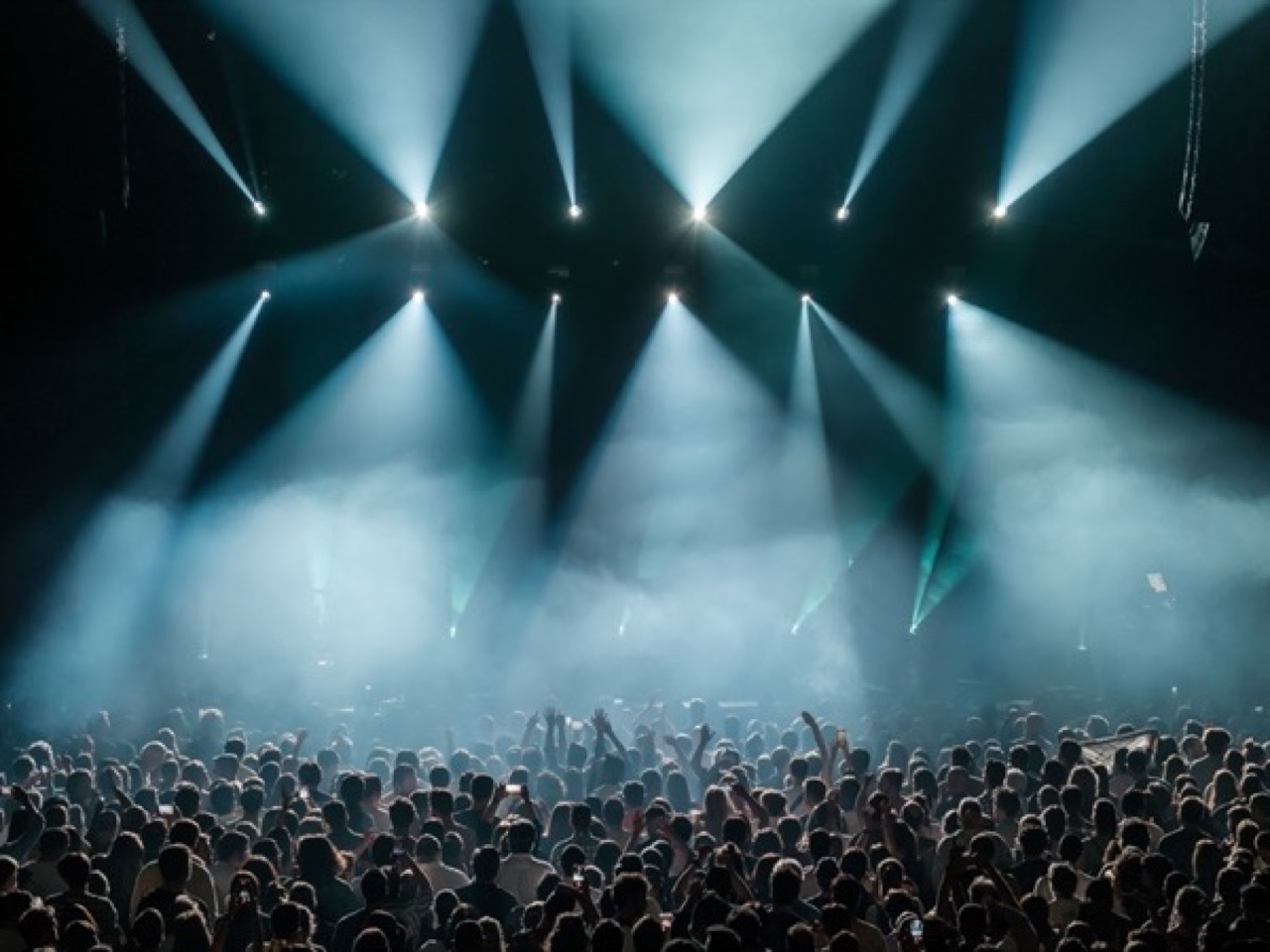White light beams over a concert crowd in the dark
