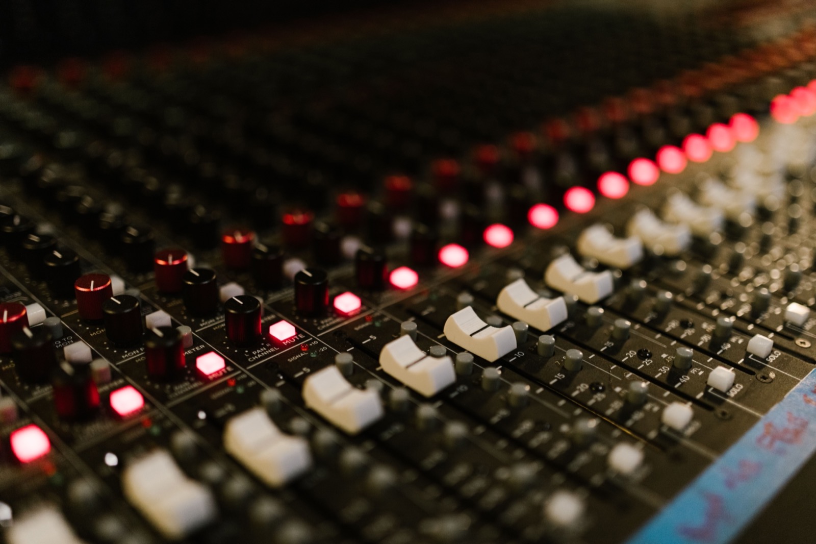Faders and lit buttons on a recording studio mixing console