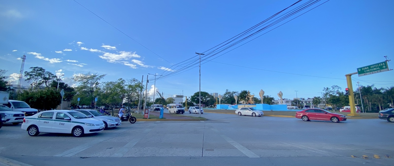 The traffic circle with giant conch shell sculptures on Avenida Tulum in downtown Cancún, with taxis and cars under a clear blue sky