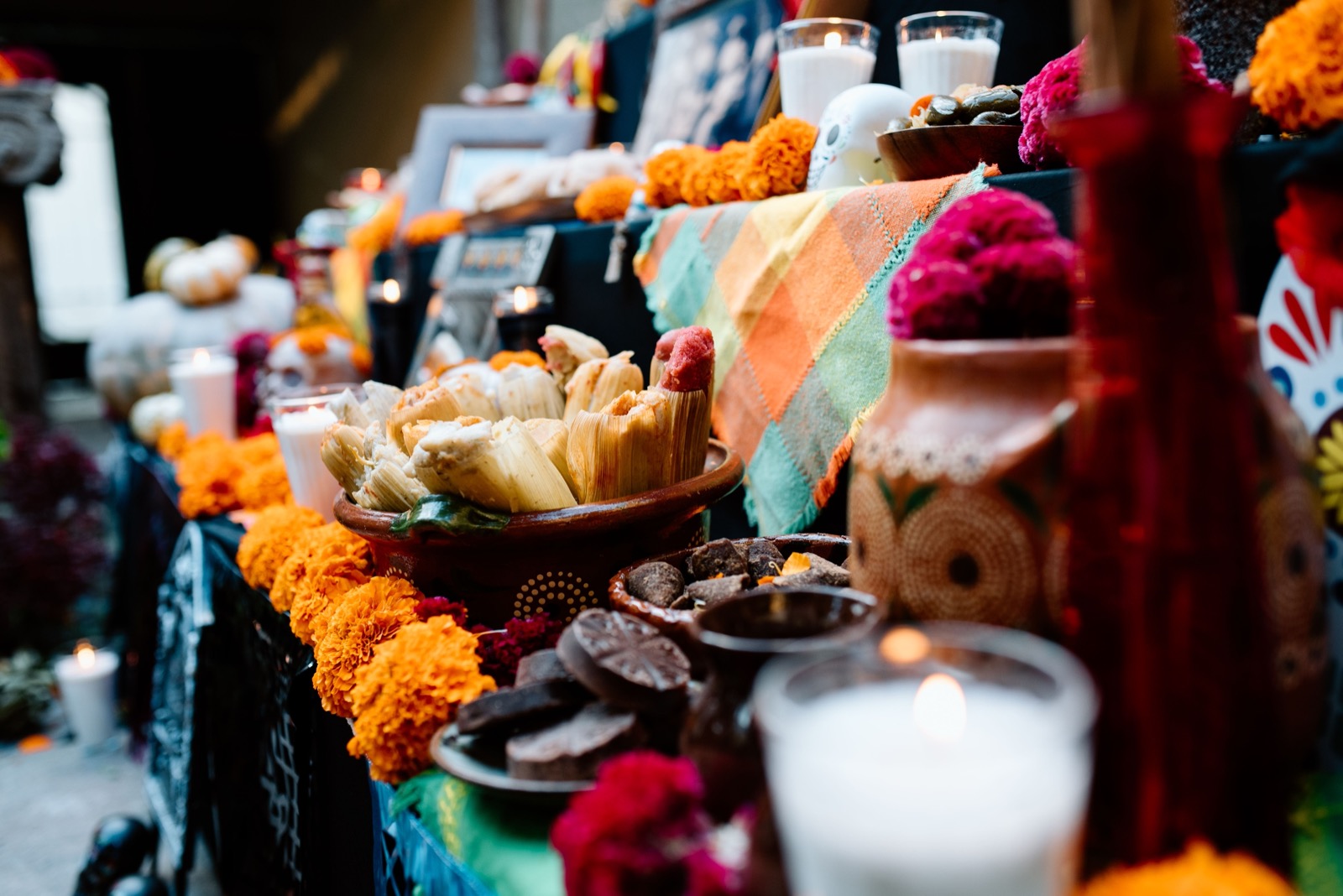 A Day of the Dead ofrenda laid with marigolds, candles, tamales and a sugar skull