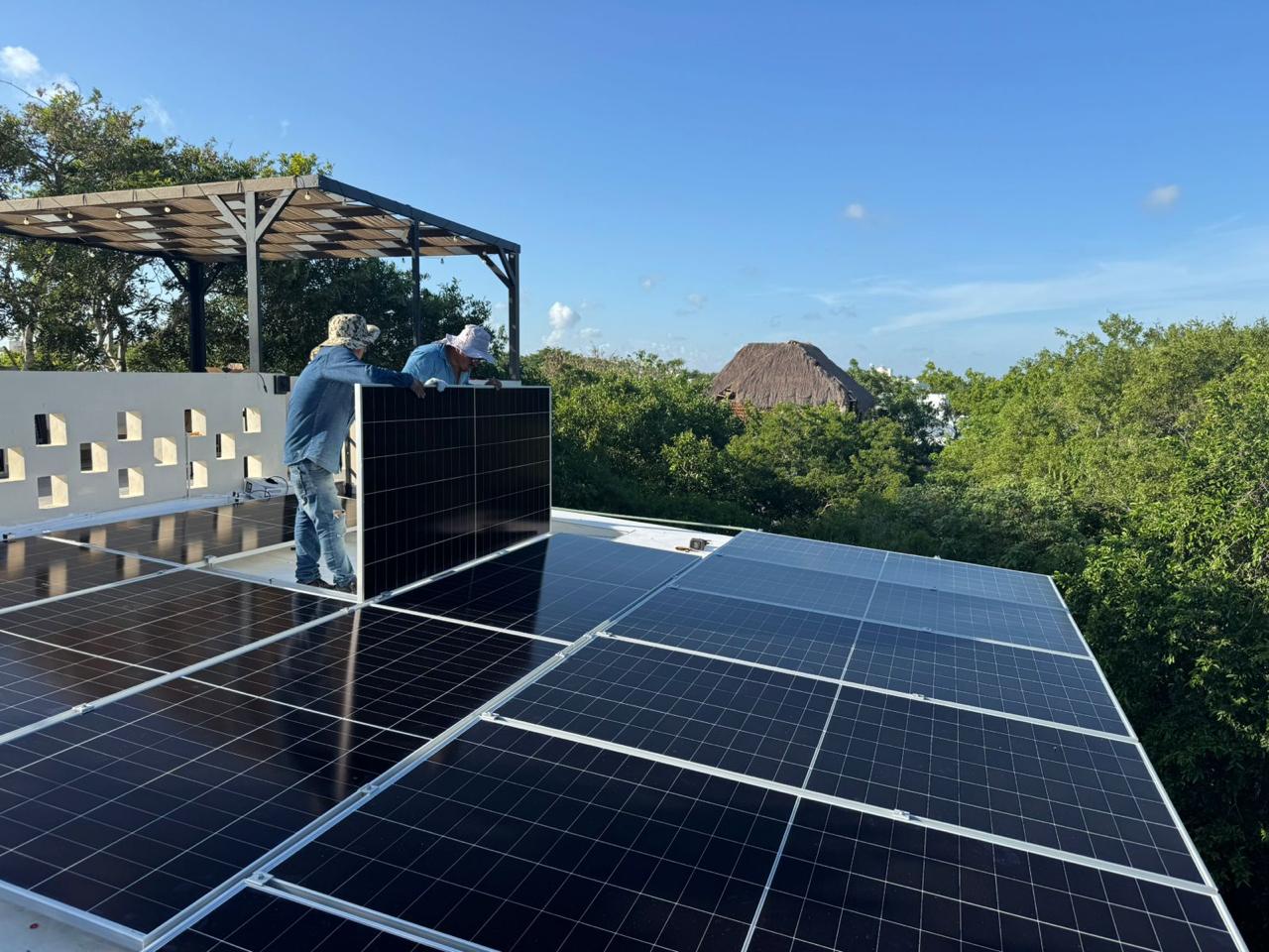 Installation crew positioning a solar panel on a Tulum rooftop