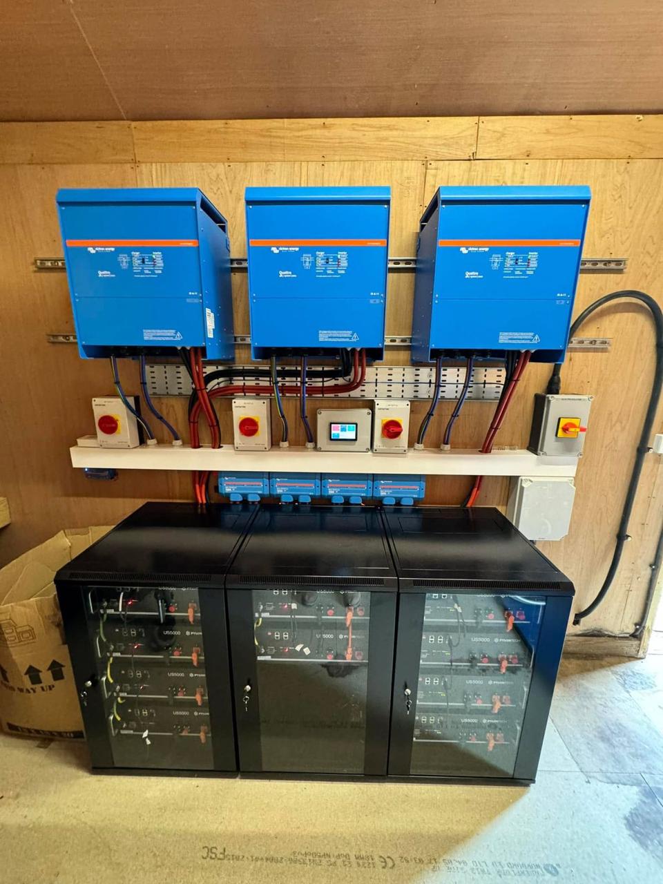 Battery storage installation with three inverters above lithium battery racks