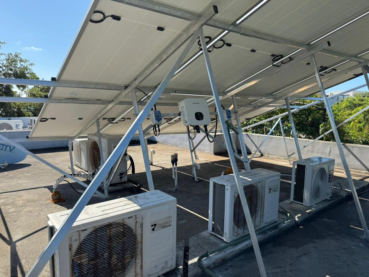 Solar array raised on a frame above rooftop air conditioning condensers