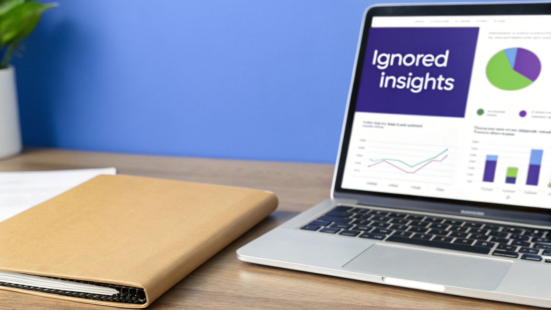 A laptop screen displays 'Ignored insights' with colorful data charts, next to a brown notebook on a wooden desk.