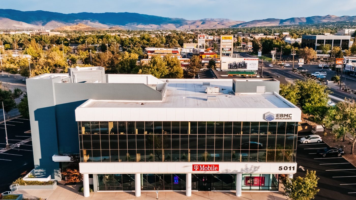 Aerial view of the EBMC Real Estate Reno office at 5011 Meadowood Mall Way, with the Sierra Nevada mountains in the background.