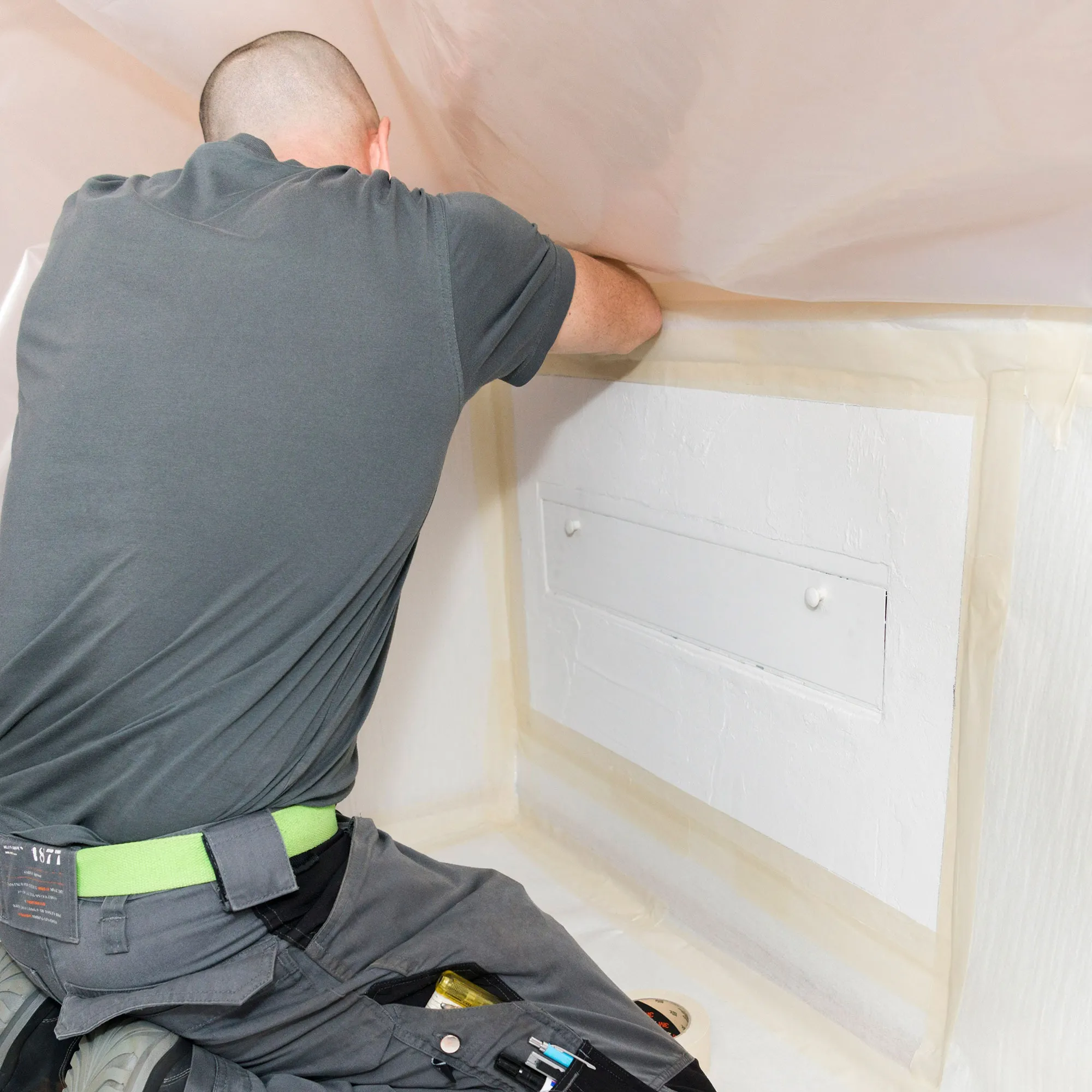 A man working on a ceiling in a room.