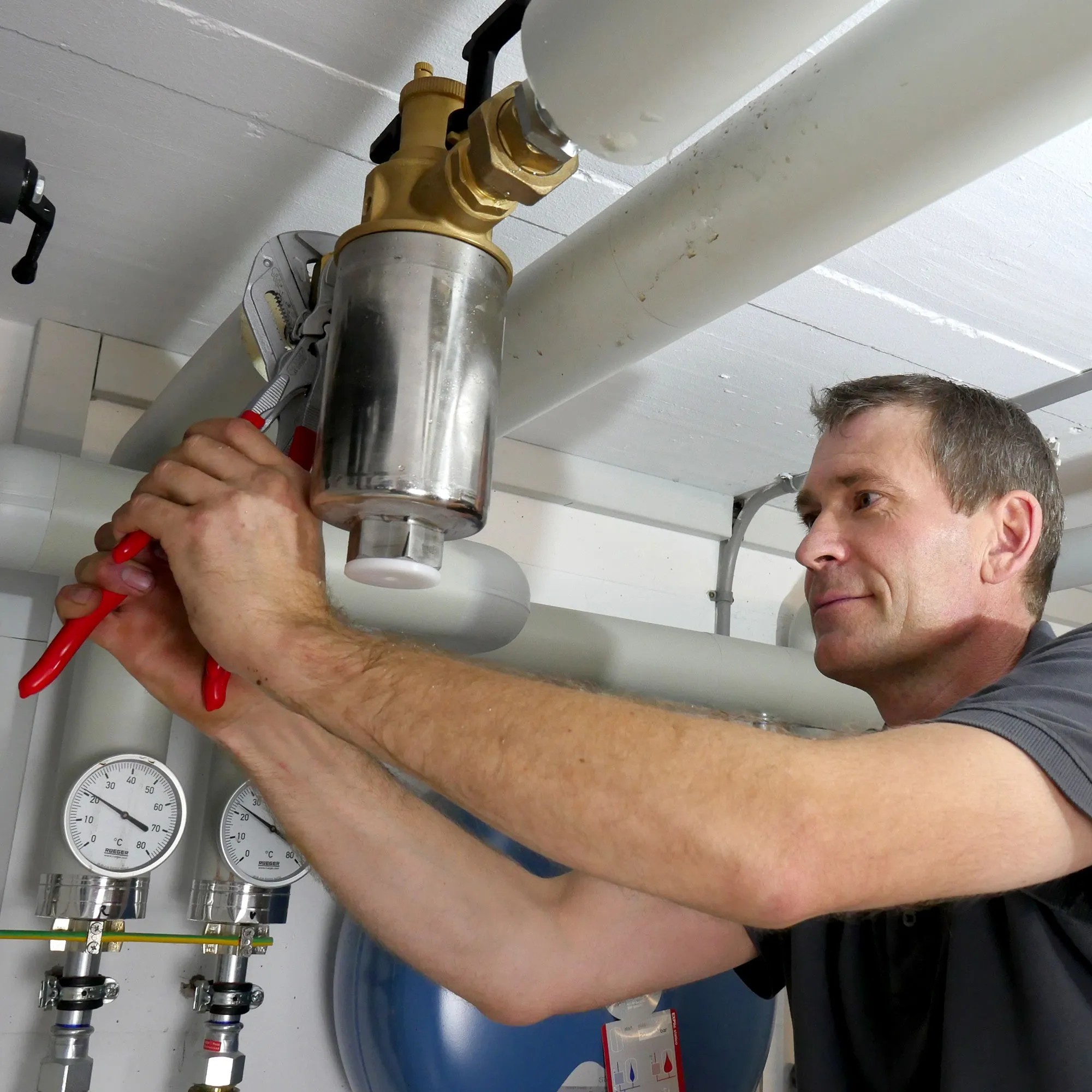 A man working on a water heater in a garage.