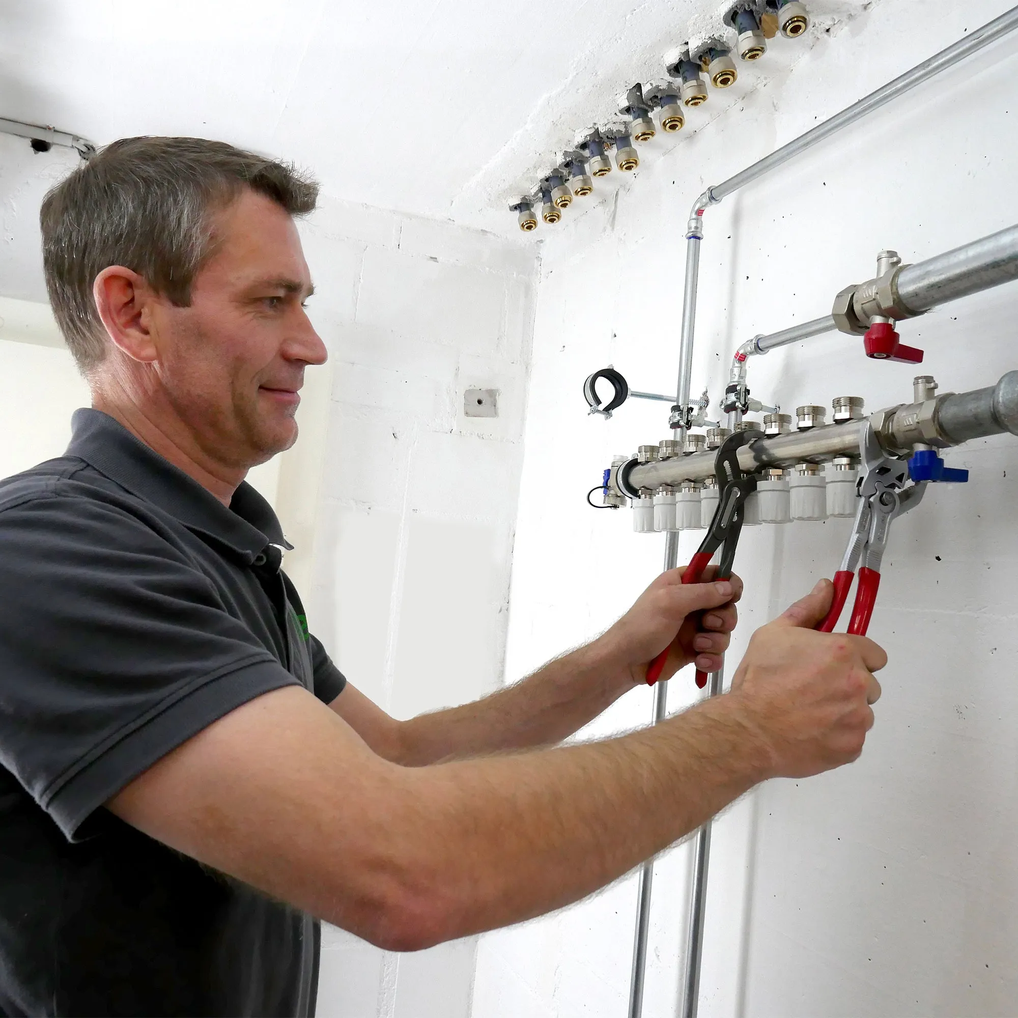 A man is working on a wall mounted water heater.