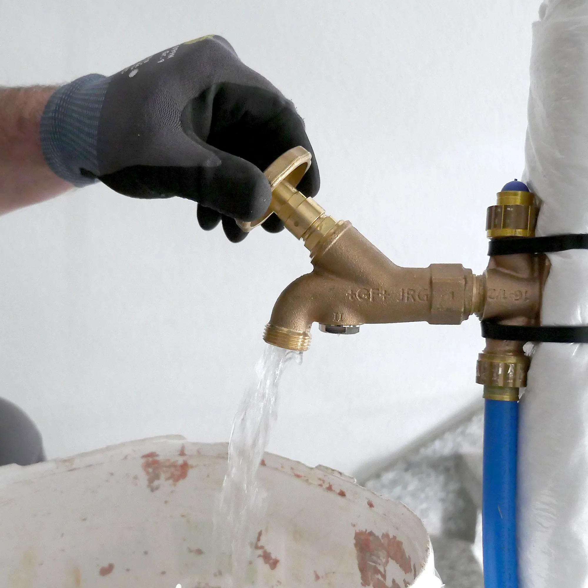 A person in black gloves and gloves is filling a faucet with water.