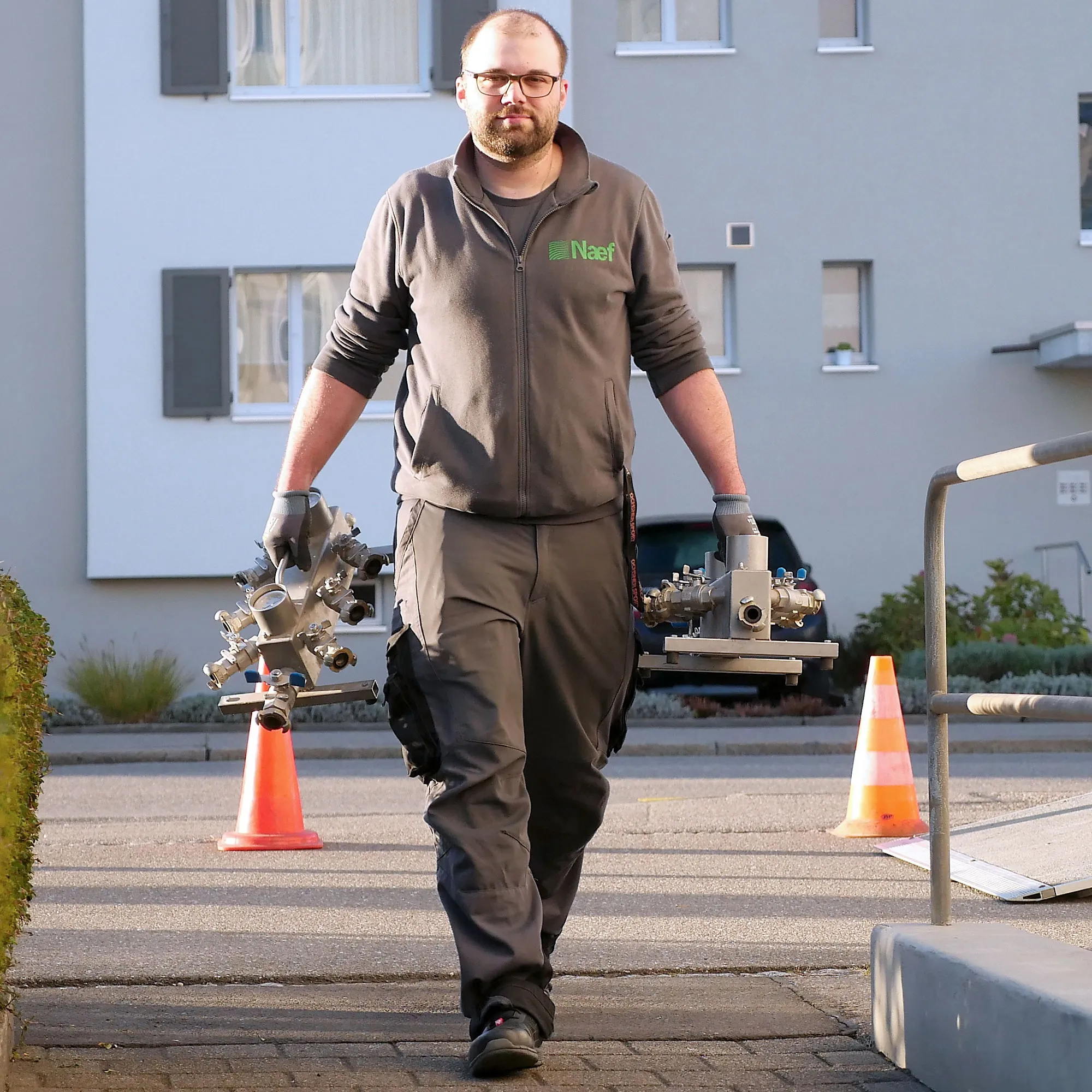 A man walking down a sidewalk with a skateboard.