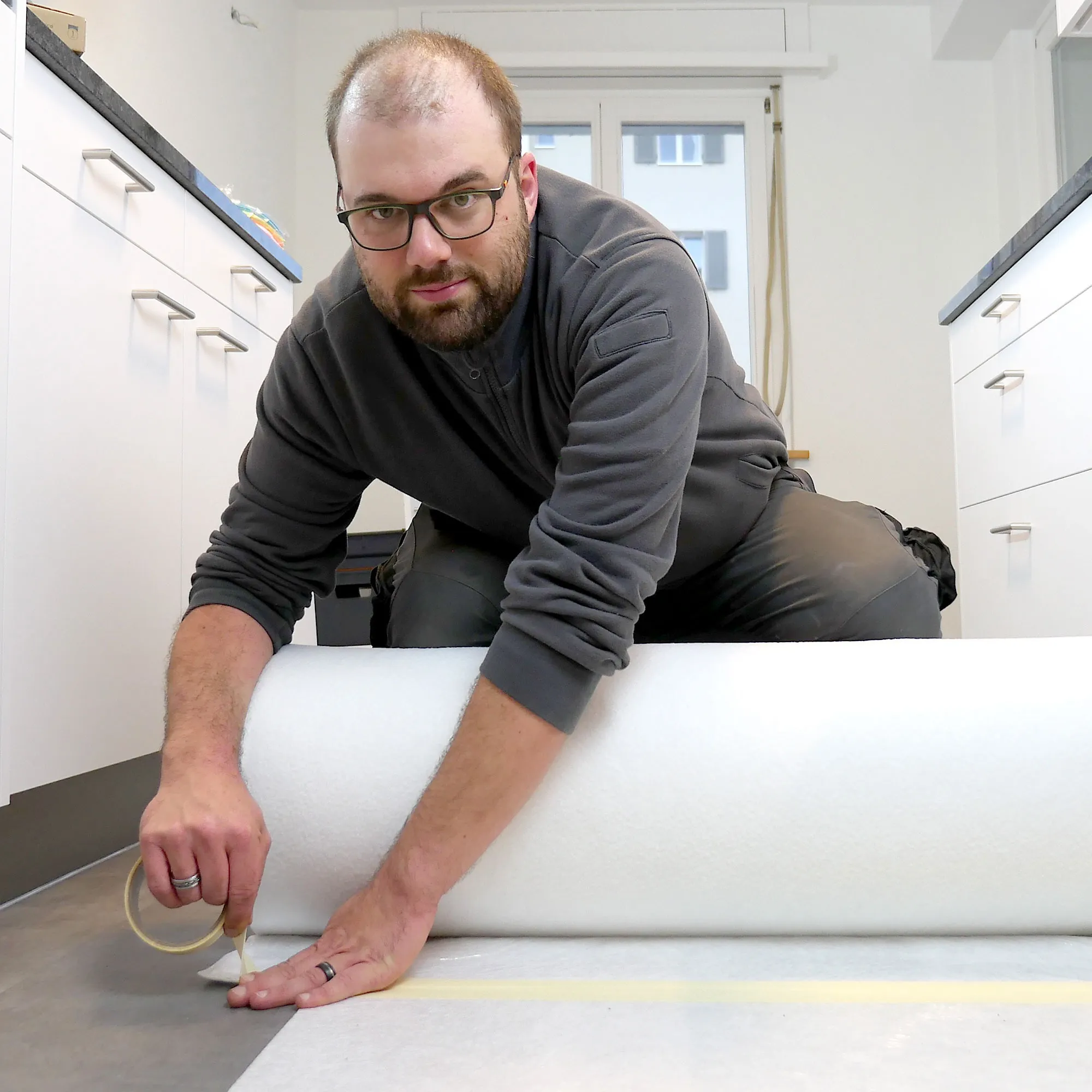 A man laying on top of a roll of white paper.