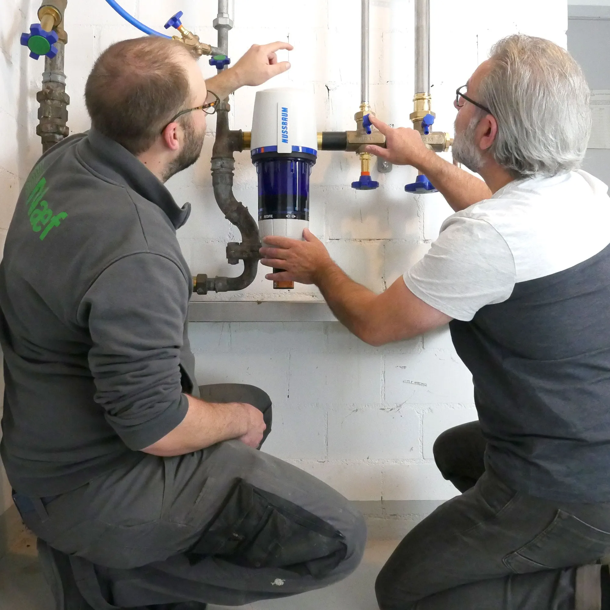 A couple of men working on a water heater.