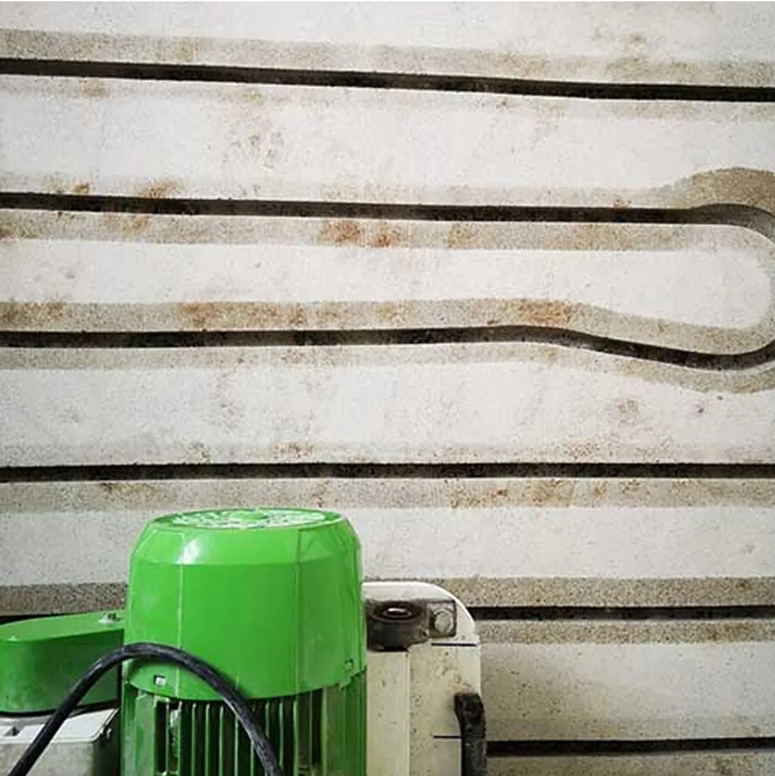 A green machine is sitting in front of a wall.