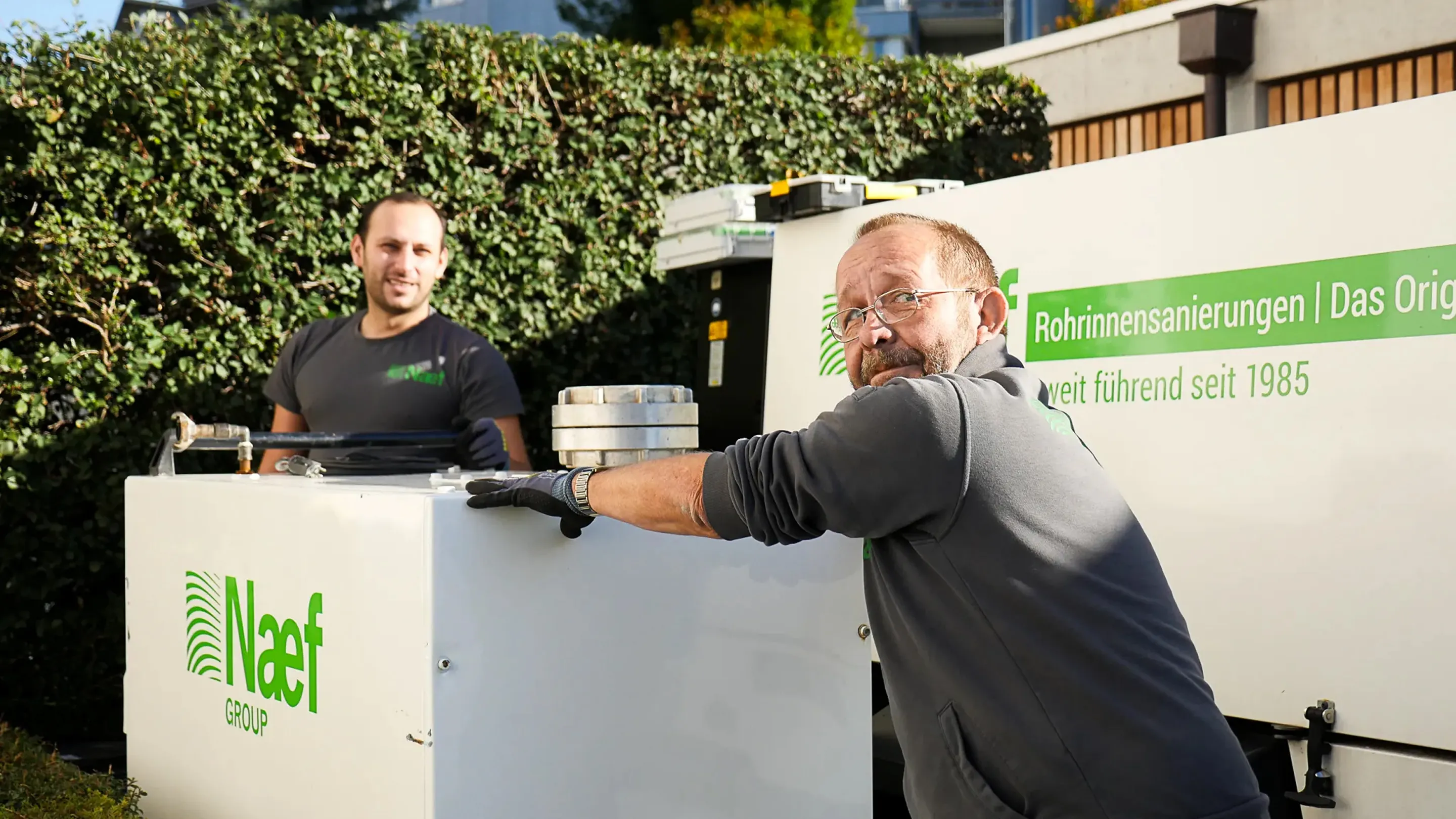 Two men standing next to a white refrigerator.