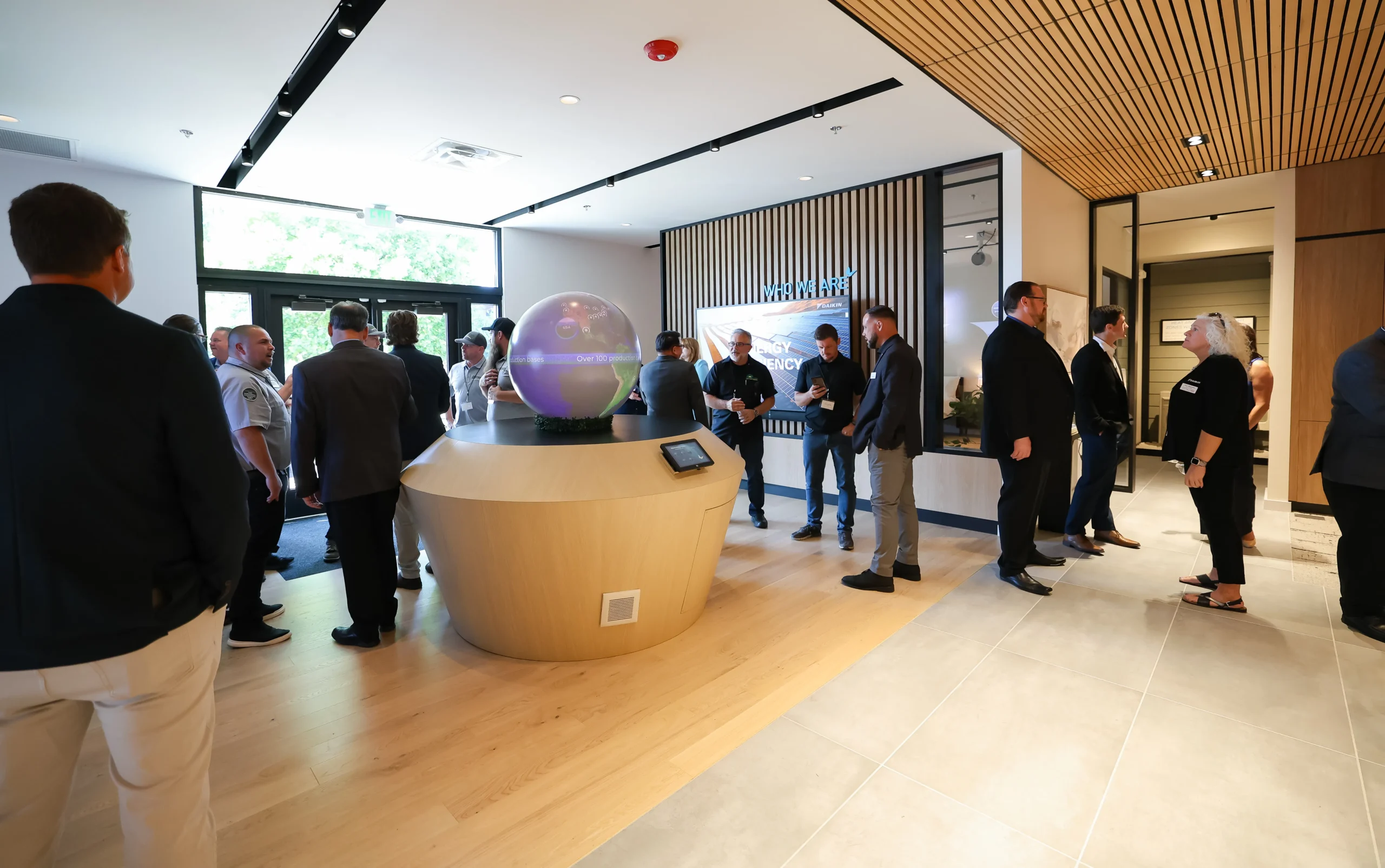 Modern office lobby with interactive globe and people gathered for meeting