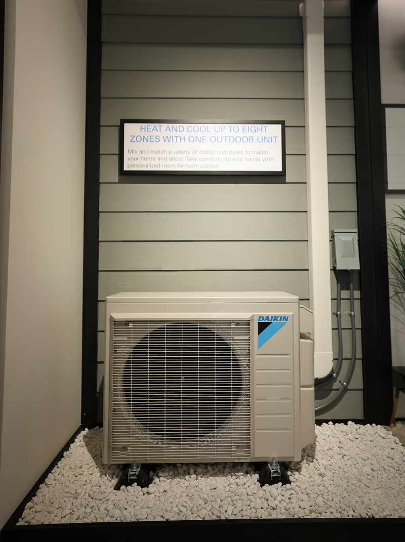 Daikin outdoor air conditioning unit on white stones with informational sign