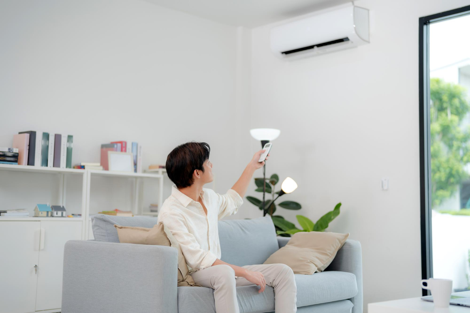 Person adjusting smart home lighting with remote control while sitting on couch