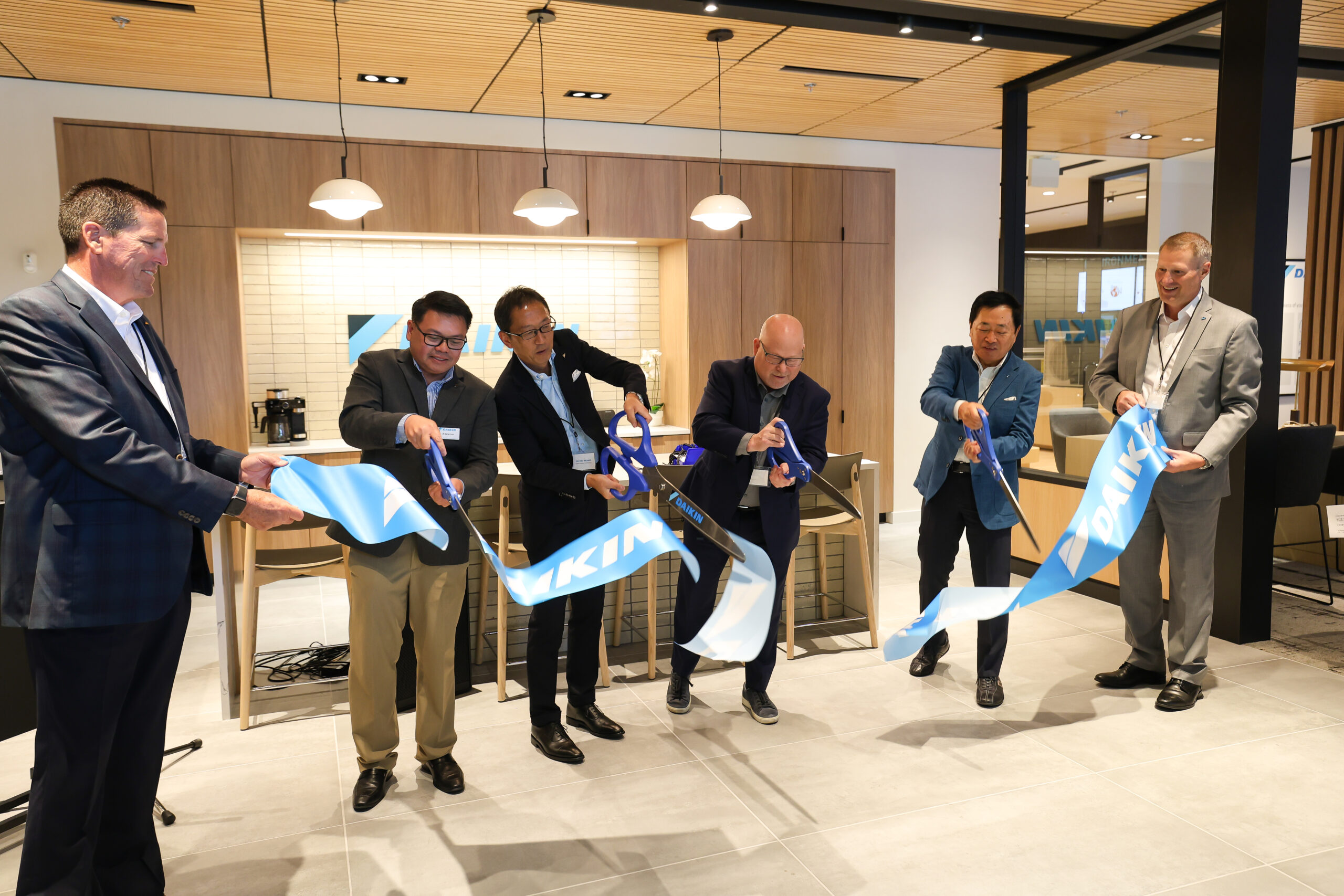 Business executives cutting blue ribbons at corporate office opening ceremony