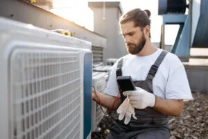 Technician in overalls checking an outdoor HVAC unit during maintenance