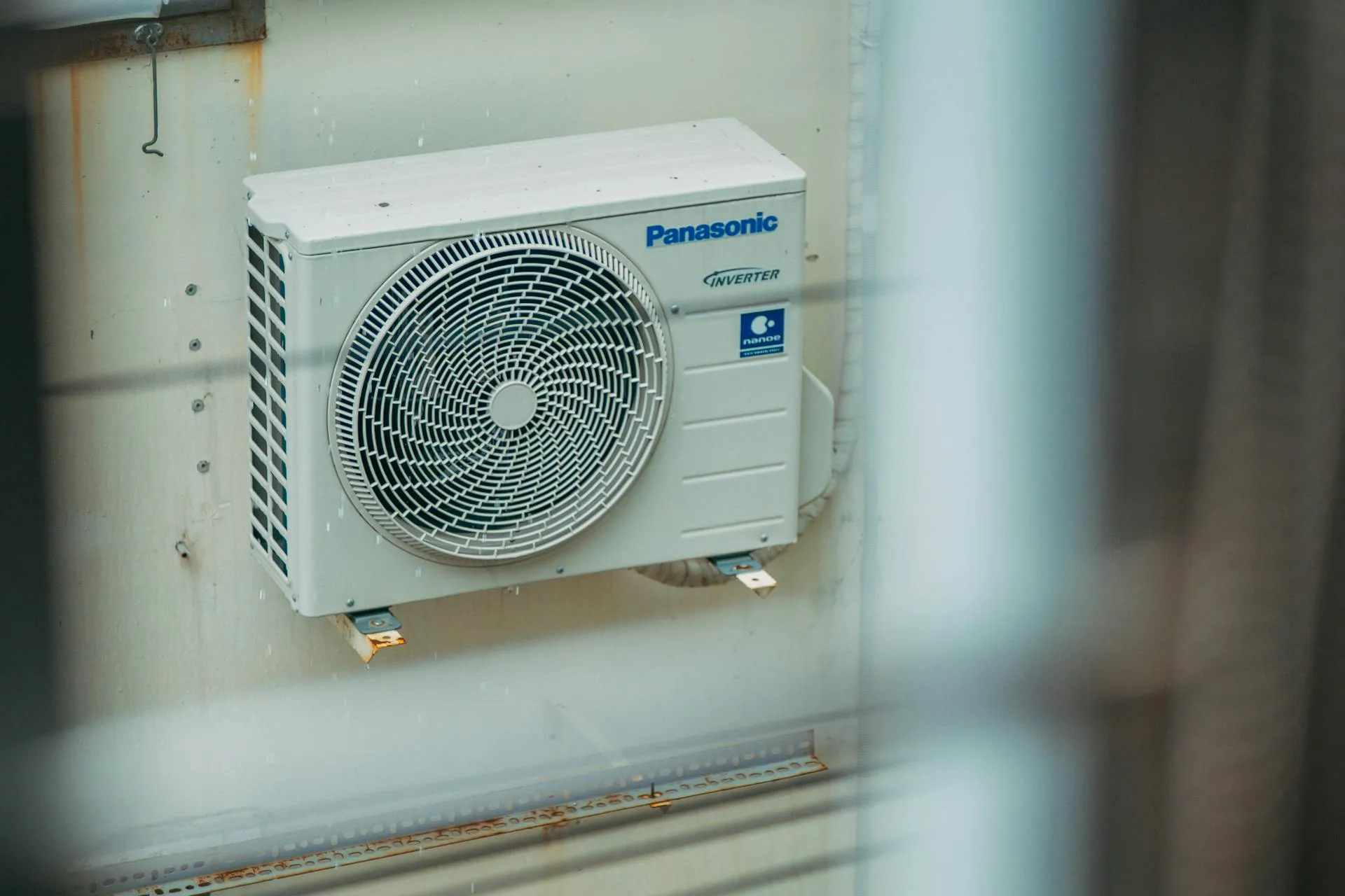 Panasonic inverter air conditioner unit mounted on weathered wall