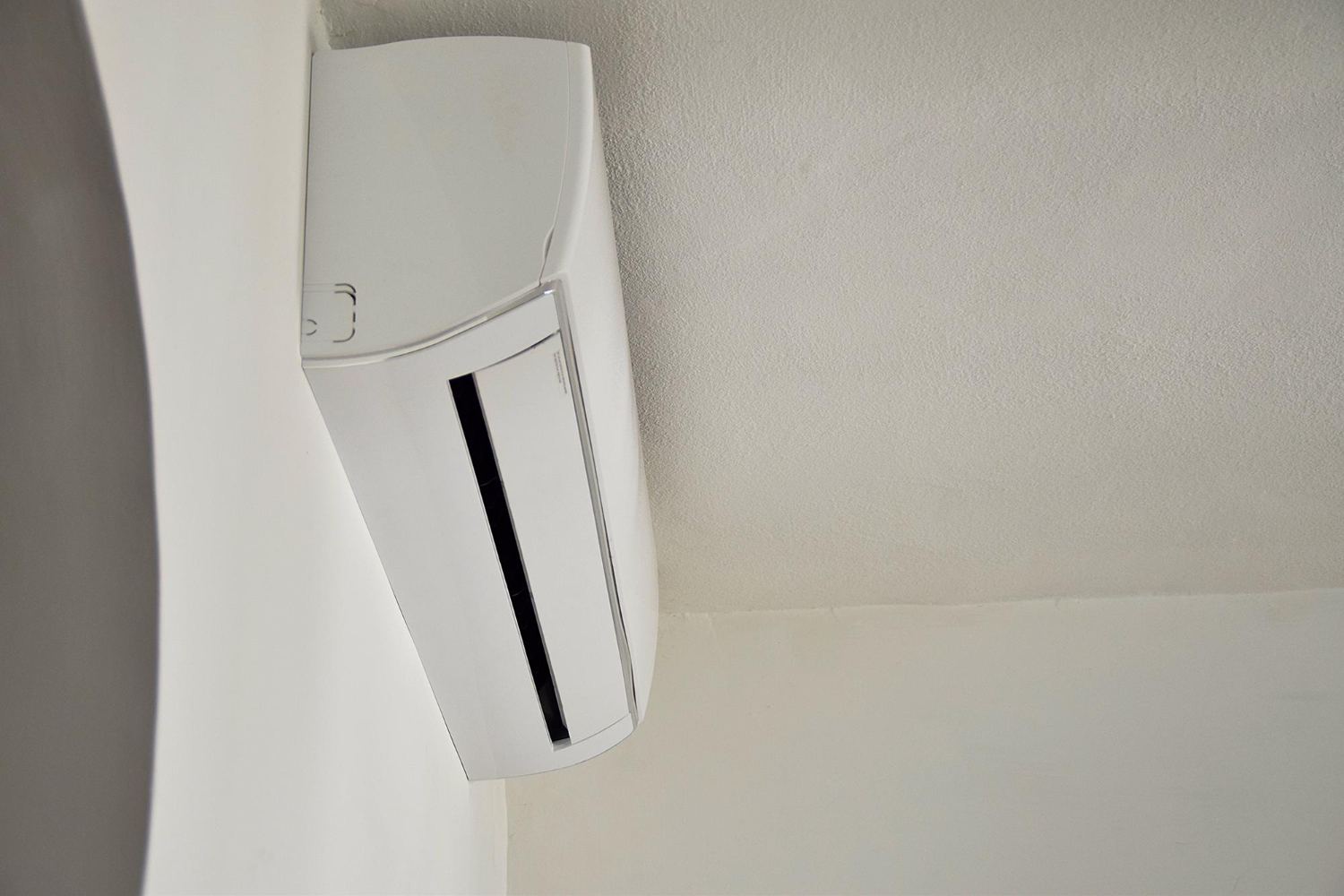 White air conditioner or heat pump mounted on a light wall