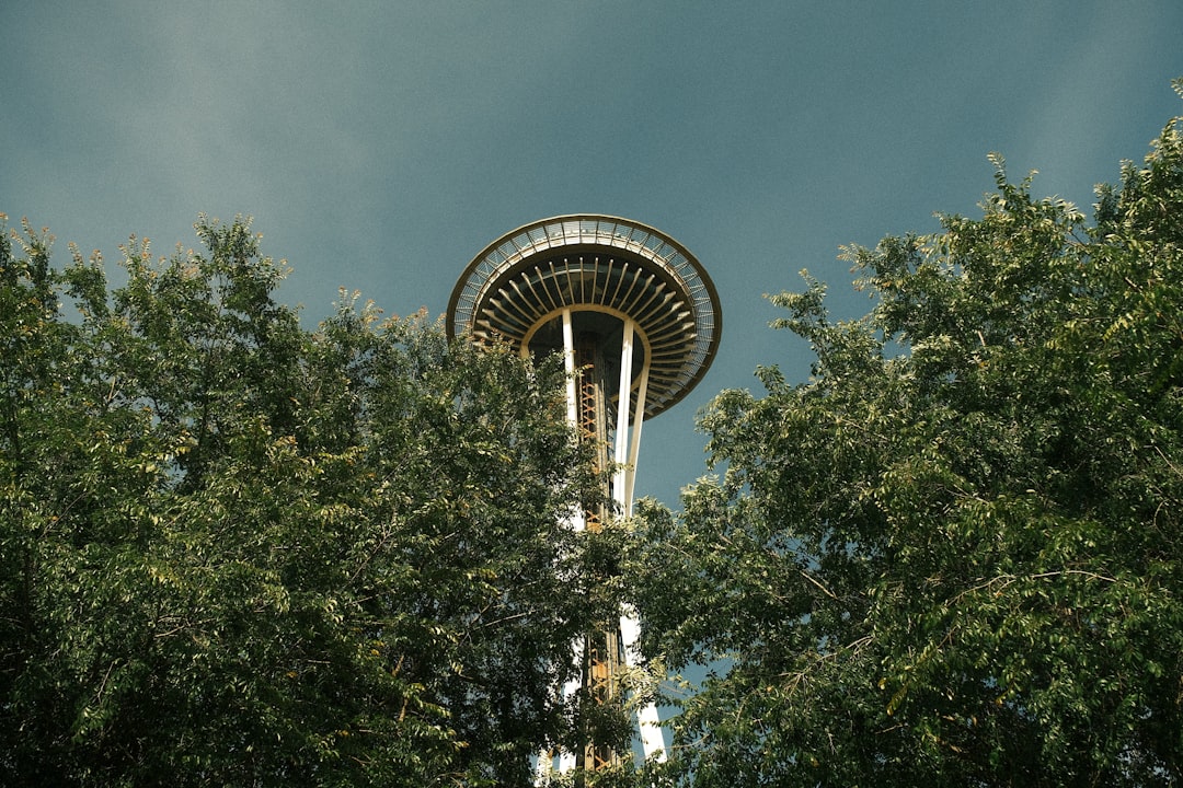 Space Needle rising above green trees against blue sky in Seattle