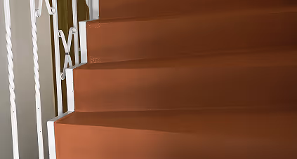 Braune Treppe mit weißem schmiedeeisernem Geländer.